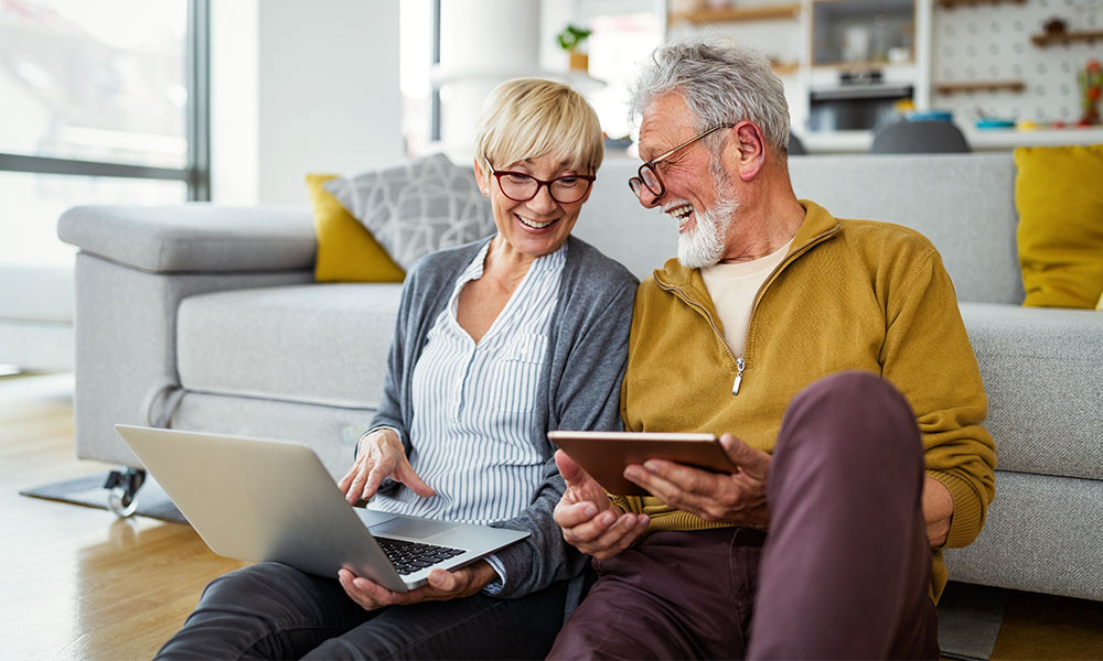 Mann und Frau die Tarife auf einem Tablet und Laptop vergleichen